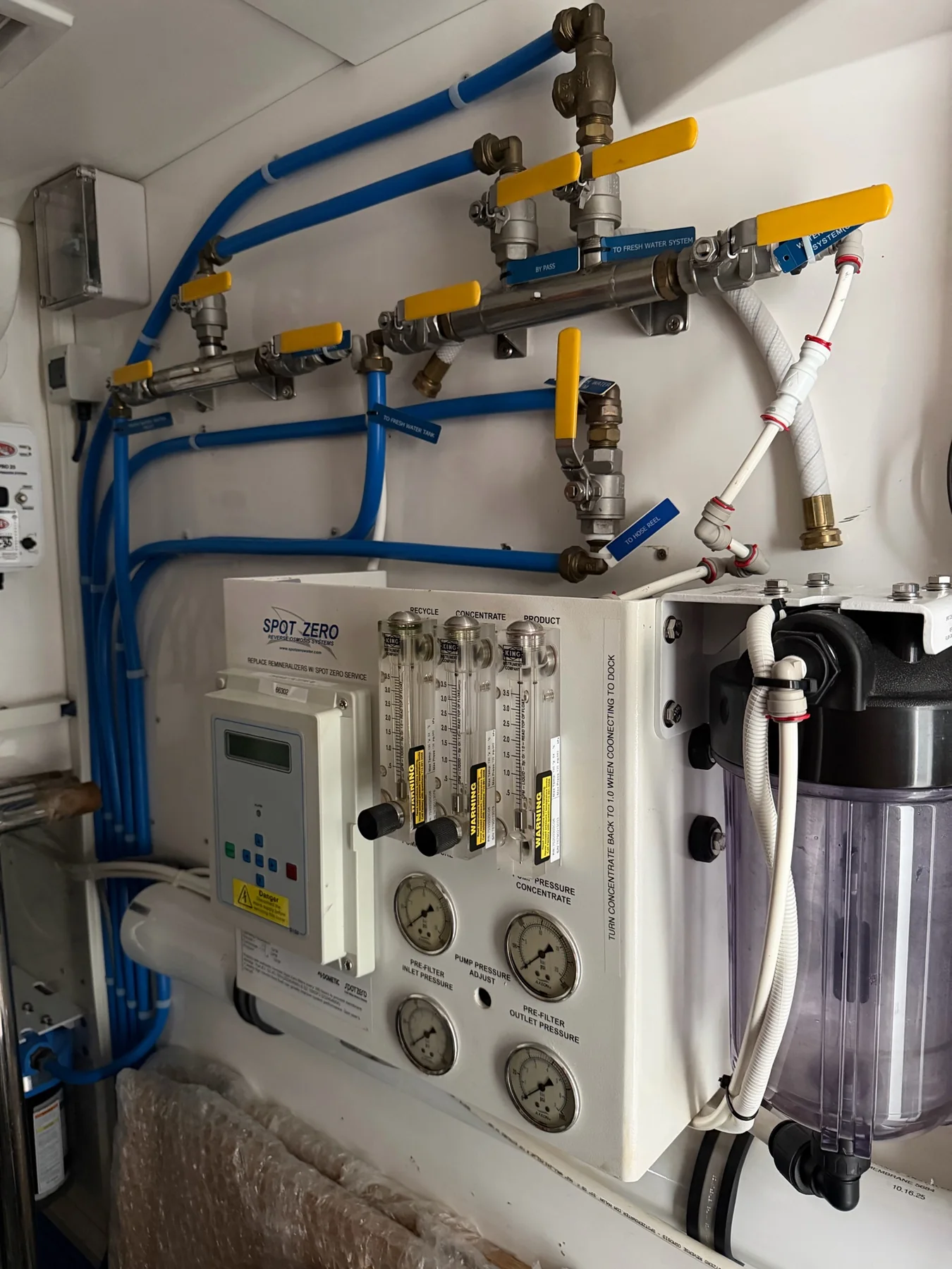 Marine reverse-osmosis watermaker with gauges, flow meters, filters, valves, and blue plumbing lines
