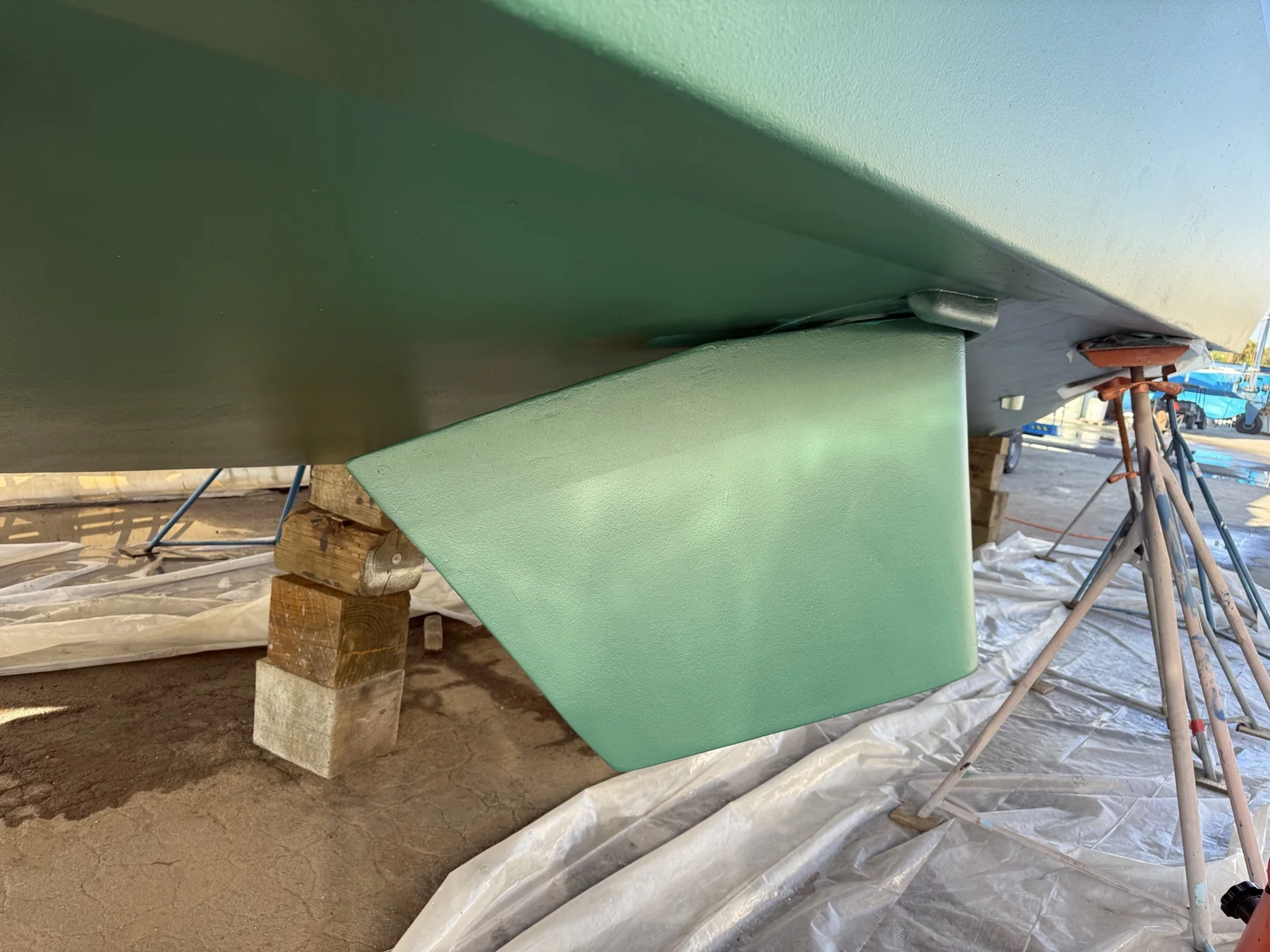 Green marine stabilizer fin installed on a vessel hull in a boatyard